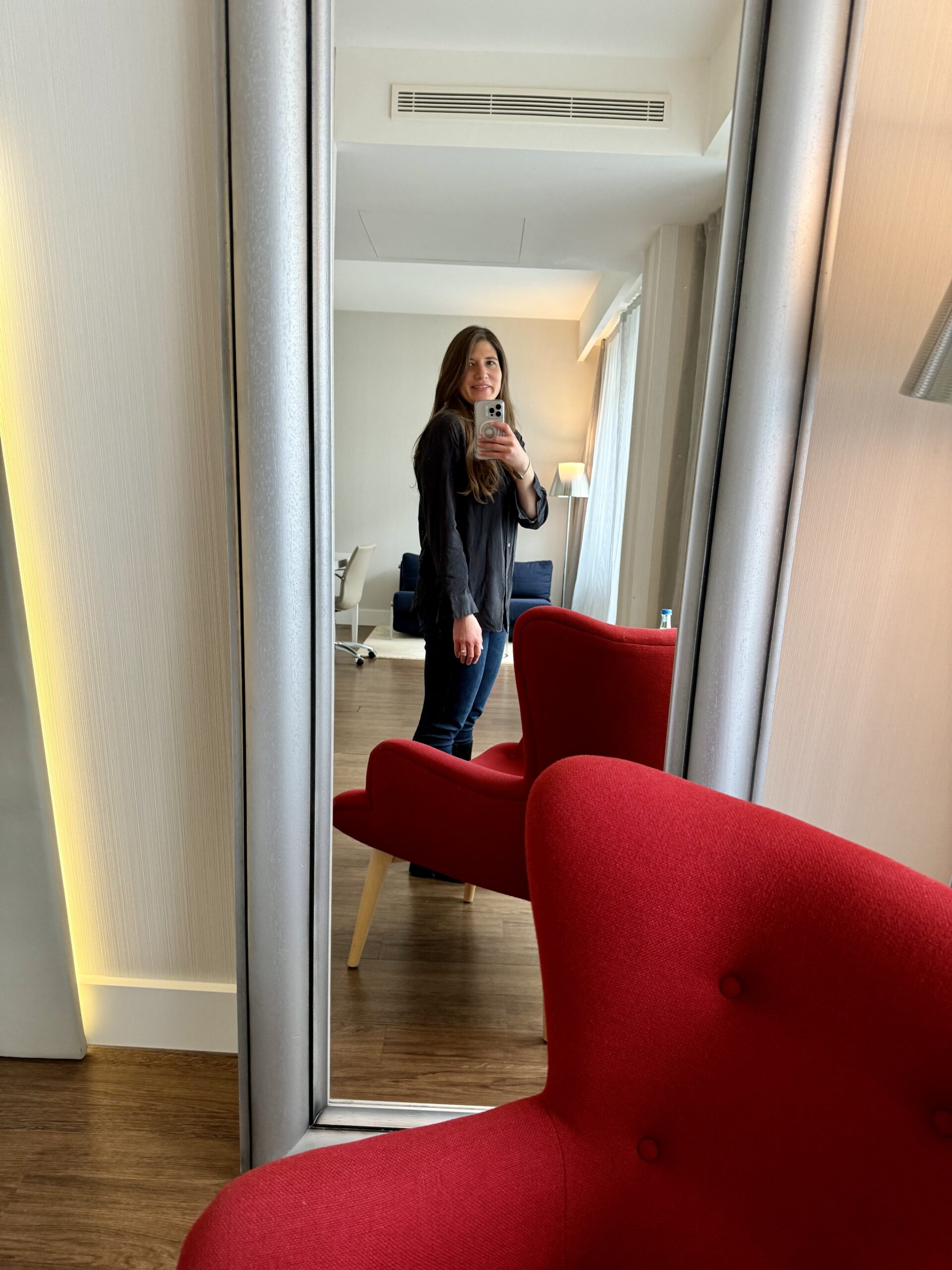 Allie in mirror in hotel room with red chair